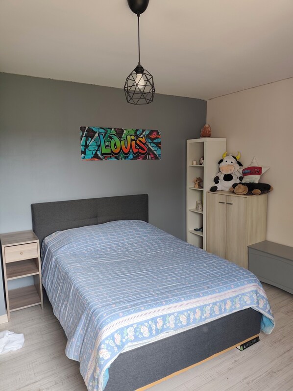 A bedroom with a bed, a nightstand, a wardrobe, and a wall decoration.