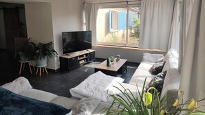 A modern living room with a flat-screen TV, sofas, a coffee table, and potted plants. - Country house (Saint-Sylvestre-sur-Lot)