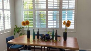Ein Essbereich mit Holztisch, blauen Stühlen und Sonnenblumen in Vasen.