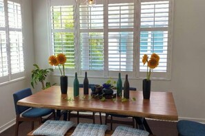 A dining area with a wooden table, blue chairs, and sunflowers in vases. - Furnished Townhome with Sauna, Cold Plunge, and Hot tub. Short-term available (St. Petersburg)