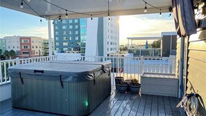 Ein Whirlpool auf einer Holzterrasse mit Blick auf Gebäude im Hintergrund.