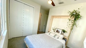 Ein Schlafzimmer mit Bett, Schrank, Deckenventilator und einer Topfpflanze.