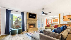 Ein Wohnzimmer mit Kamin, einer Couch, einem Fernseher und Blick ins Freie.