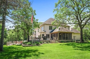 A two-story house with a covered porch, a flagpole, and a well-maintained lawn.