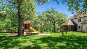 A residential area with a play structure, a house, and a lawn. - LL Unit w/ Private Access in Luxurious Riverfront Vacation Home (Oak Grove)