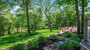 A lush garden with a pond, stone pathway, and outdoor seating area. - LL Unit w/ Private Access in Luxurious Riverfront Vacation Home (Oak Grove)