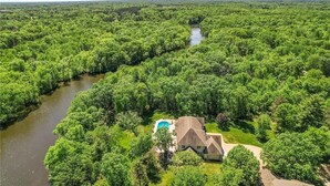 A house surrounded by dense forest, a river, and a swimming pool. - LL Unit w/ Private Access in Luxurious Riverfront Vacation Home (Oak Grove)