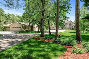 A residential area with two houses, a driveway, and a well-maintained lawn.