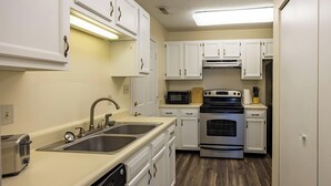 A kitchen with white cabinets, stainless steel appliances, a dishwasher, and a microwave. - Keystone Garden Villa G (Indianapolis)