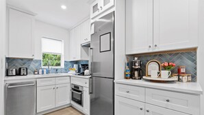 Una cocina moderna con armarios blancos, electrodomésticos de acero inoxidable y un salpicadero de azulejos en patrón de espiga.