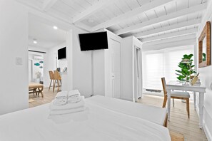 A modern hotel room with a bed, a desk, a television, and a view of the outdoors. - Delray Beach Cottage • Jul/Aug Deal (Delray Beach)