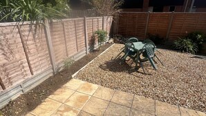 A patio with a table and chairs, a wooden fence, and a building in the background. - Park House Sleeps 4 With Enclosed Garden (Northampton)