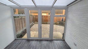 A room with a sloped ceiling, a skylight, and a view of a backyard with a wooden fence and gravel path. - Park House Sleeps 4 With Enclosed Garden (Northampton)