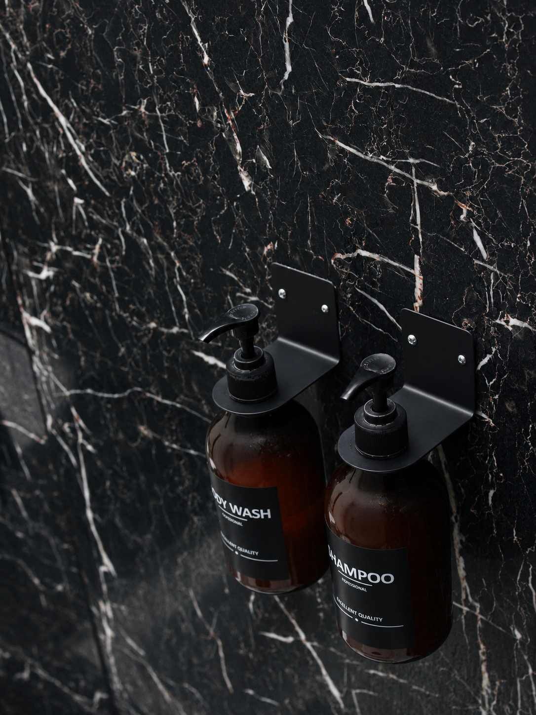 Two bottles of shampoo and body wash mounted on a black marble wall.
