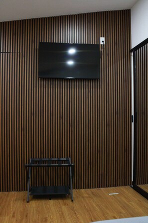 A room with a television mounted on a wooden slatted wall, a bench in the foreground, and a door to the right. - Private Room, Zona Consulado (Zapopan)