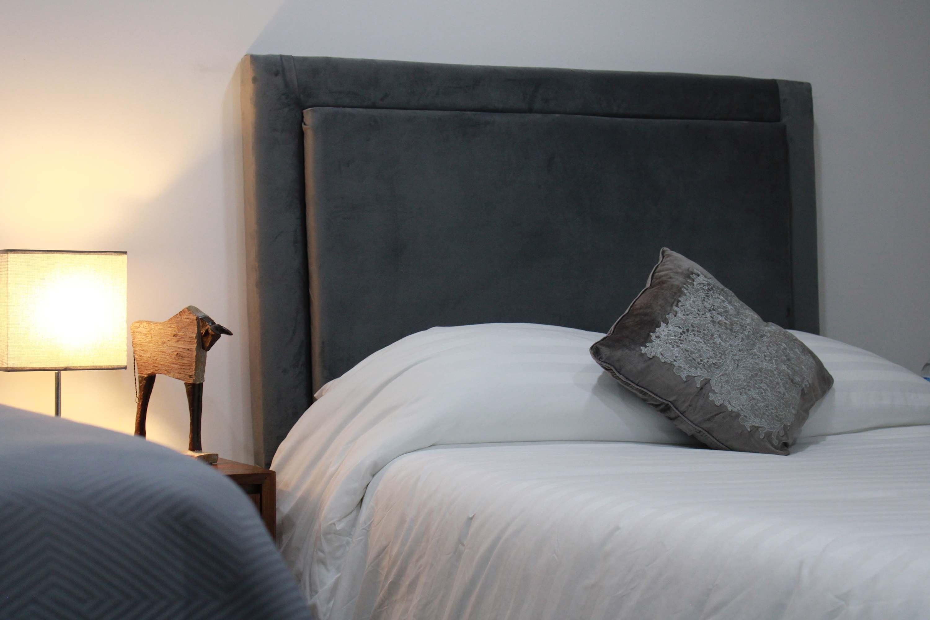 Ein Schlafzimmer mit einem großen Bett, einem Nachttisch mit Lampe und einem dekorativen Gegenstand.
