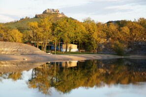 Aussicht auf einen See mit einem Hügel, Bäumen und einem Gebäude auf der Spitze.