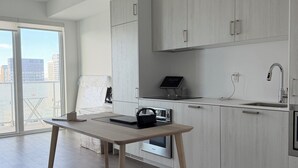 Una cocina moderna con armarios blancos, una mesa de madera y vistas a la ciudad.