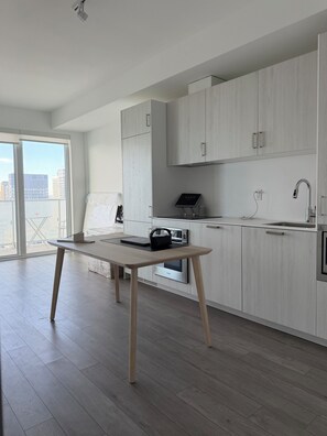 Eine moderne Küche mit weißen Schränken, einem Holztisch und Blick auf die Stadt.