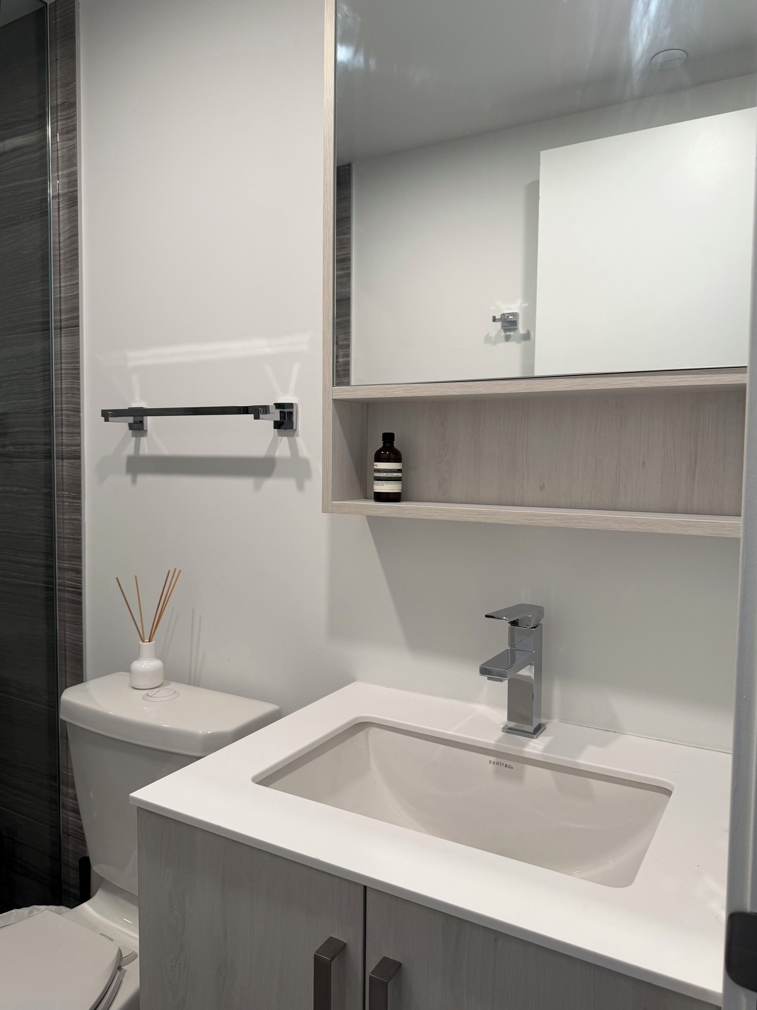 Ein modernes Badezimmer mit einem weißen Waschbecken, einem Spiegel und einer Toilette.
