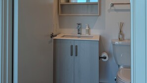 Un baño moderno con lavamanos, espejo, inodoro y toallero.