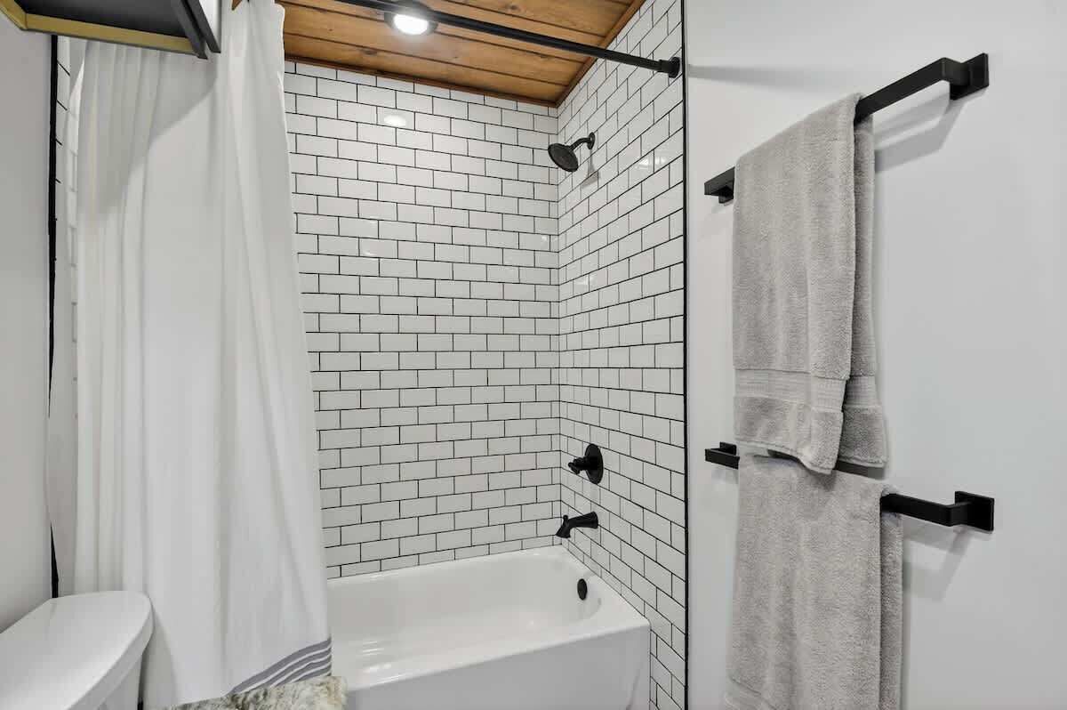 Une salle de bain avec une baignoire blanche, une douche et un porte-serviettes.