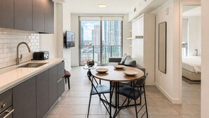 Eine moderne Küche mit Essbereich, einem an der Wand montierten Fernseher und einem großen Fenster mit Blick auf die Stadt.
