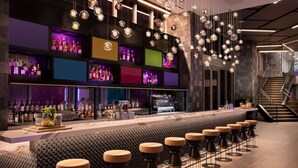 Eine Bar mit einer langen Theke, Hockstühlen und hängenden, kugelförmigen Leuchten.