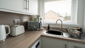 Een moderne keuken met een ingebouwde magnetron, broodrooster en spoelbak.
