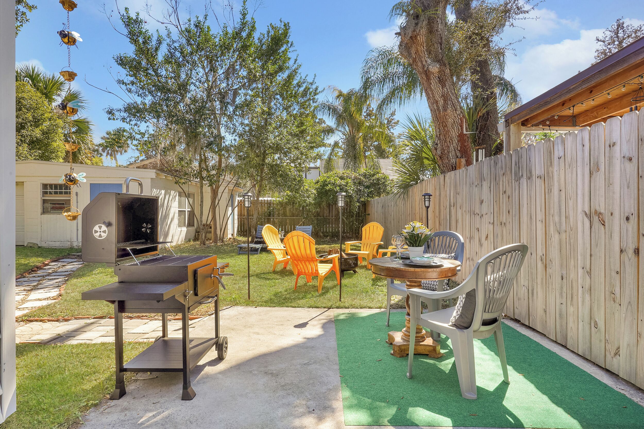 Un patio trasero con una parrilla, mobiliario exterior y una valla de madera.