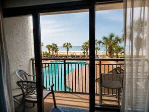 Ein Balkon mit Pool, Stühlen und Blick auf Strand und Meer.