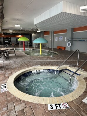 Ein Hallenbad mit Whirlpool, Wasserrutschen und einem Rettungsschwimmer-Schild.