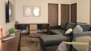 Ein modernes Wohnzimmer mit einer Couch, einem Couchtisch, einem Fernseher und einem Essbereich mit Stühlen und Tisch.