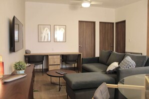 A modern living room with a sofa, a coffee table, a TV, and a dining area with chairs and a table. - MS Suite Acogedora Homeoffice Ubicadísima (Santiago de Querétaro)