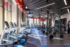 Une salle de sport équipée de matériel d’exercice, notamment des tapis de course et des appareils de musculation, et dotée d’une grande fenêtre qui laisse entrer la lumière naturelle.