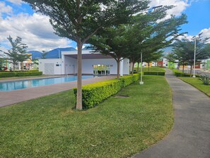 Una piscina, un camino pavimentado y un edificio con entrada de vidrio.