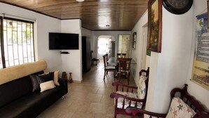 Una sala de estar con sofá, sillas, televisor y un comedor con mesa y sillas.