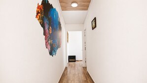 Un pasillo con una gran obra de arte abstracta en la pared izquierda, un cuadro enmarcado a la derecha y piso de madera.