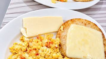 Dos platos de huevos revueltos con queso y tostadas.