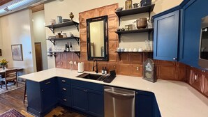 A modern kitchen with a central island, built-in appliances, and wooden cabinetry. - Suite A at The Elliott 1887 (LeRoy)