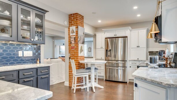 A modern kitchen with a central island, stainless steel appliances, and a brick accent wall. - Coastal Wells Cottage with Deck and Fire Pit (Wells)