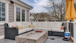 A covered outdoor seating area with a sectional sofa, a concrete coffee table, and a gas grill. - Coastal Wells Cottage with Deck and Fire Pit (Wells)
