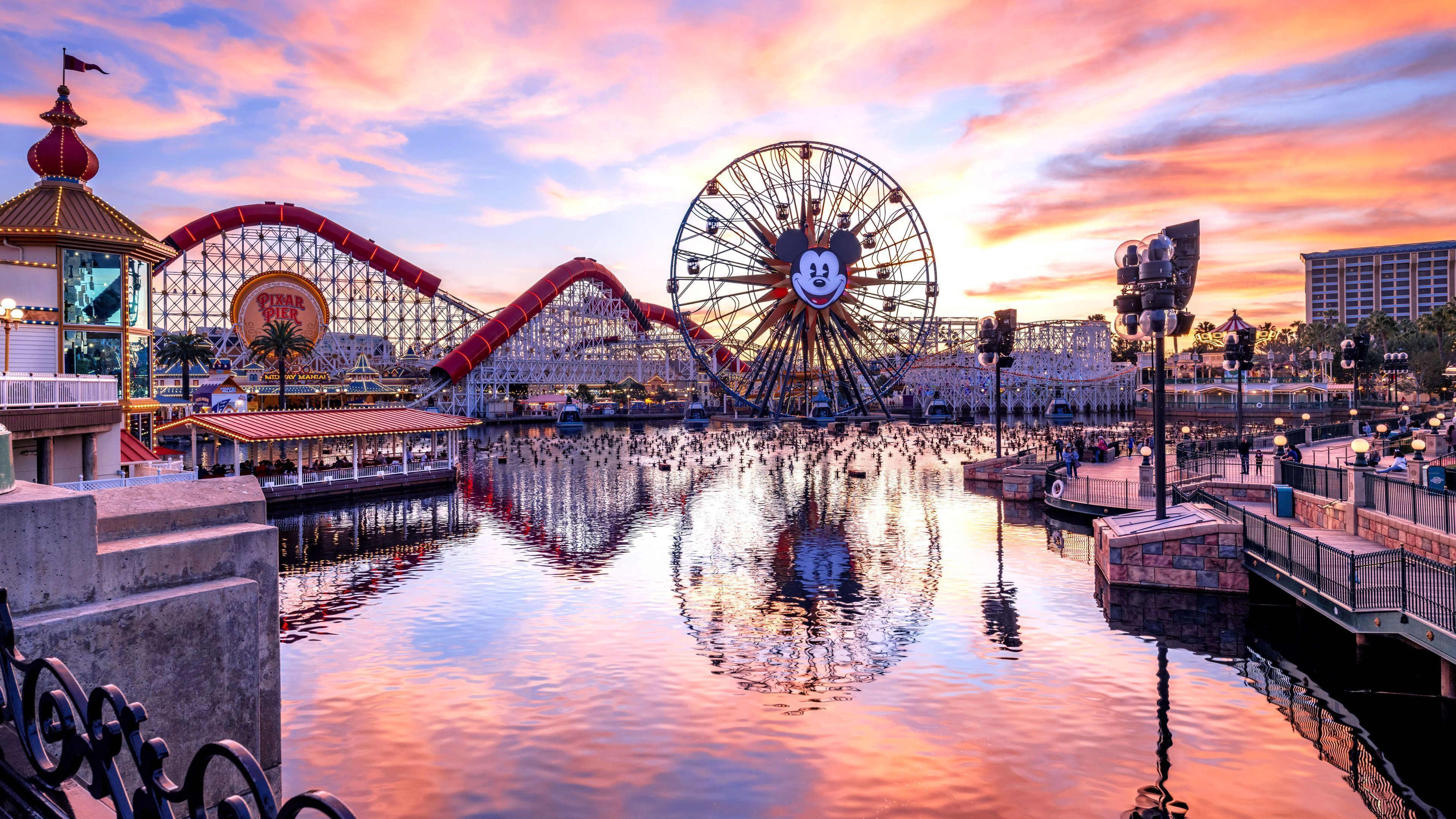 A water body reflecting amusement park rides and structures.