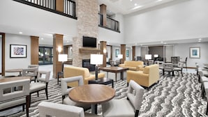A spacious lobby with multiple seating areas, a fireplace, and a large screen.