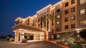 A multi-story hotel with a well-lit entrance, palm trees, and a clear sky. - Accessible 1BR Suite w/ Kitchen | Free Breakfast! (Irvine)