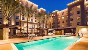 A hotel with a swimming pool, palm trees, and multiple buildings. - Cozy Studio | Kitchen, Breakfast & Fire Pit (Irvine)