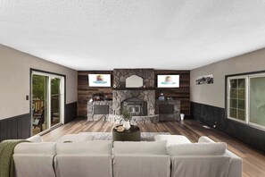 A living room with a fireplace, a sofa, and a television. - Family Friendly_5BR Sleeps10_Near Downtown KC_FIFA (Independence)