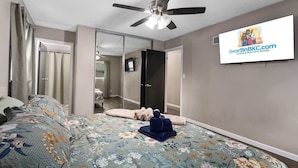 A bedroom with a bed, a ceiling fan, a television, and a mirror. - Great Home_ Sleeps 10_Close to Arrowhead_Football (Independence)