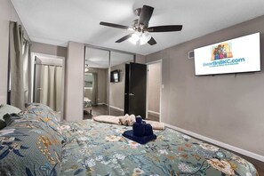 A bedroom with a bed, a ceiling fan, a television, and a mirror. - Family Friendly_5BR Sleeps10_Near Downtown KC_FIFA (Independence)