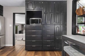 A kitchen with dark cabinetry, a microwave, and a window with a view. - Family Friendly_5BR Sleeps10_Near Downtown KC_FIFA (Independence)